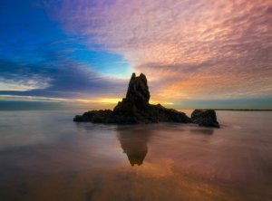 Beautiful sunset behind seaside rock column