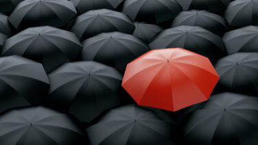 Red umbrella among sea of black ones