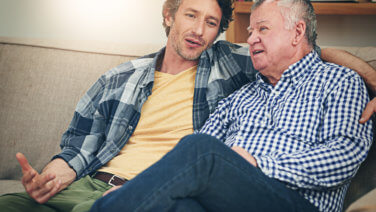 Mature man chatting with his father, at home on the sofa