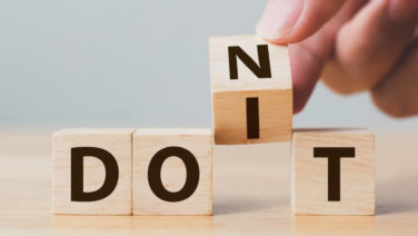 Letter blocks spell "DON'T" as hand rotates one block to spell "DO IT."